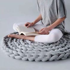 a woman is sitting on the floor reading a book