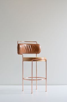 a chair with a leather seat and back rest in front of a white wall,