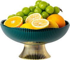 a bowl filled with oranges and limes on top of a gold pedestal base