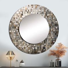 a round mirror sitting on top of a wooden table next to a vase and lamp