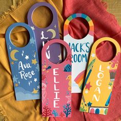 three wooden door hangers with different designs on them sitting on a red cloth covered table