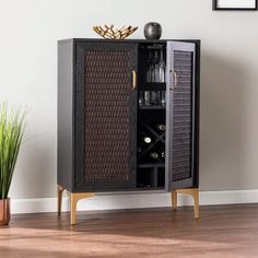 a wooden cabinet with wine bottles in it next to a vase filled with pink flowers