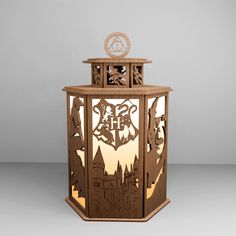 a wooden lantern with laser cut designs on the front and sides, depicting hogwart's castle