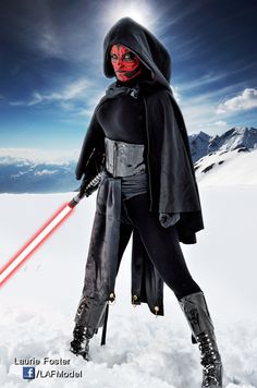 a woman dressed as darth vader standing in the snow with a lightsaben on