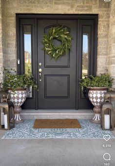 the front door is decorated with two planters and a wreath on it's side