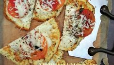 four slices of pizza with cheese and tomatoes on them sitting on a piece of parchment paper