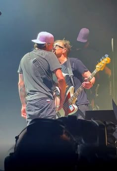 two men standing on stage with guitars in their hands