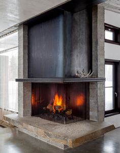 a fire place in the middle of a living room with concrete walls and flooring