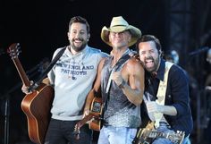 two men are holding guitars and smiling at the camera