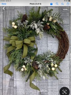 a christmas wreath with pine cones and greenery on a wooden background, ready to be hung