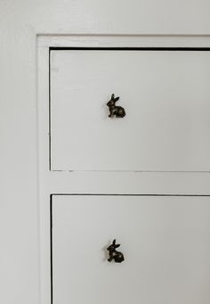 two white drawers with metal knobs on the top one has a black rabbit head