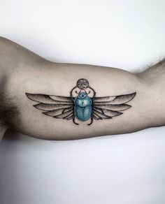 a blue beetle tattoo on the left arm and right arm, with an insect in it's center