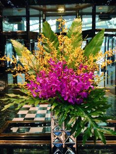 a vase filled with purple and yellow flowers on top of a checkerboard floor