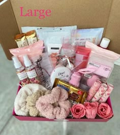 a pink box filled with lots of different items and flowers on top of a table