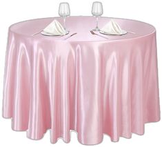 a pink table cloth with two wine glasses on top and napkins in the middle