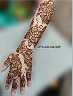 a woman's hand with henna tattoos on her arm and hands, showing the intricate