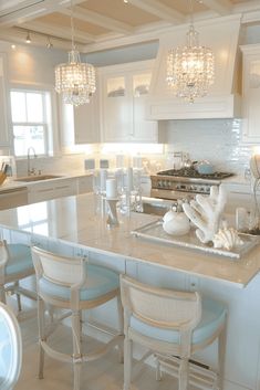 a large kitchen with white cabinets and marble counter tops, chandeliers hanging from the ceiling