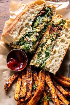 a sandwich and some french fries on a piece of parchment paper with ketchup