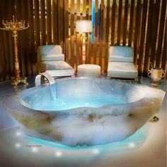 a large bath tub sitting in the middle of a room next to two white chairs