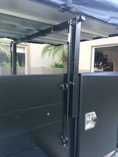 the back end of a truck with an open door and black cover on it's side