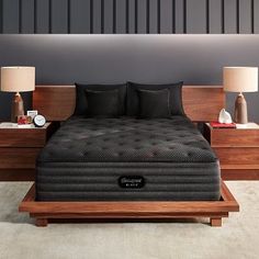 a bed sitting on top of a wooden platform next to two lamps and a night stand