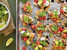 an assortment of nachos with avocado, tomatoes and black olives