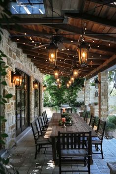 an outdoor dining area with wooden table and chairs, lights hanging from the ceiling over it