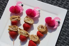 some strawberries are on a white plate with pink flamingos in the shape of pretzels