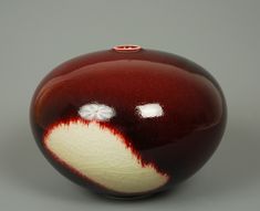 a red and white vase sitting on top of a table