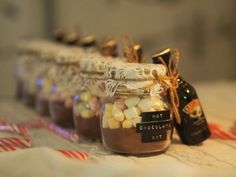 small jars filled with hot chocolate and marshmallows on a tablecloth next to candy canes