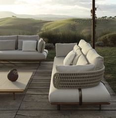 an outdoor living area with couches and tables on the ground, overlooking rolling hills