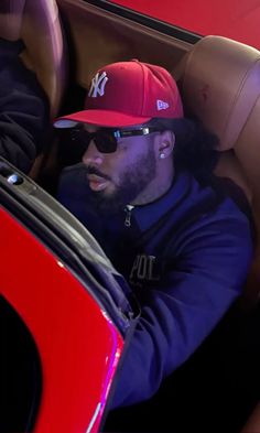 a man wearing a red hat and sunglasses sitting in a car