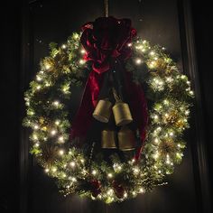 a christmas wreath with bells hanging from it's side and lights on the front