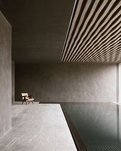 a chair sitting in the middle of a room next to a swimming pool with an open window