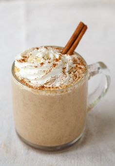 there is a cup of hot chocolate with whipped cream and cinnamon sticks in it on the table