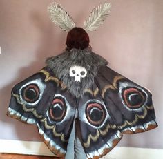 a large butterfly with feathers on it's wings and a skull in the middle