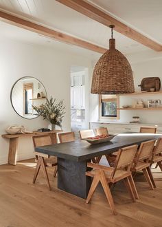 a dining room table with chairs and a basket hanging from the ceiling