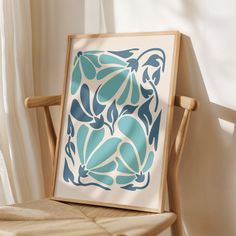 a wooden chair sitting in front of a window with a blue and white painting on it