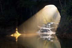 the sun shines through a tunnel into a river with waterfall cascading in it