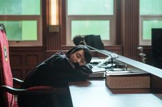 a woman sitting at a desk with her head in her hands while she sleeps on the chair