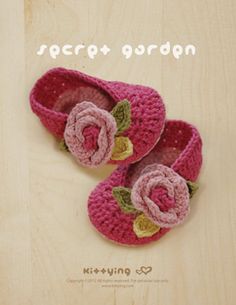 a pair of crocheted baby shoes with flowers on the front and bottom, sitting on top of a wooden surface