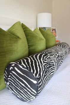 a bed with zebra print pillows and green throw pillows