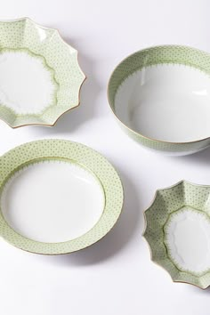 three green and white dishes sitting next to each other on top of a white table