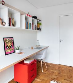 a white desk topped with a red file cabinet next to a book shelf filled with books