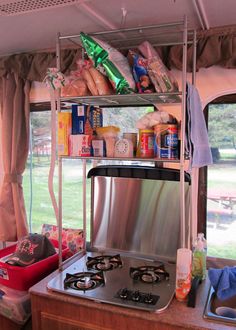 a stove top oven sitting in the middle of a kitchen next to a table with food on it