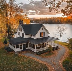 a large white house sitting on top of a lush green field next to a lake