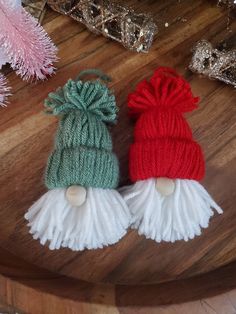 two knitted hats sitting on top of a wooden table next to pink and green decorations