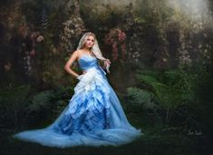 a woman in a blue and white dress posing for a photo with flowers behind her