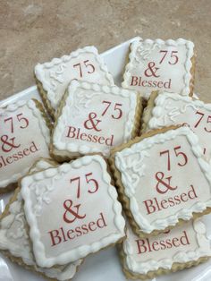 decorated cookies with white frosting and red lettering are arranged on a plate that says 75 and 85