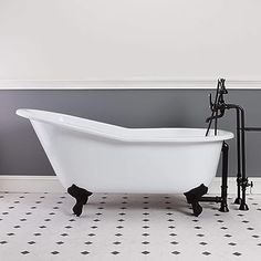 a white bath tub sitting on top of a black and white tile floor next to a gray wall